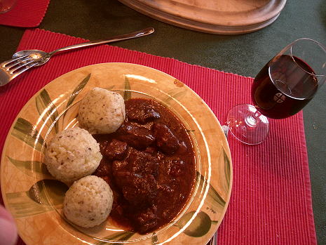 Gedeckter Tisch mit Kartoffelklößen, Gulasch, Rotwein 